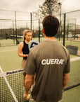 Model wearing Cuera Oncourt Airy Logo T-Shirt in Army, lifestyle action shot on the padel court